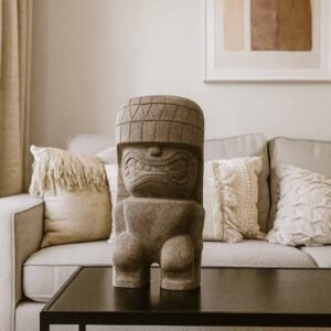 Tiki polynésien en pierre volcanique – 50 cm Primitif - Il est posé sur une table basse en tant que décoration intérieure (Visuel non contractuel - Mise en situation générée à titre indicatif)