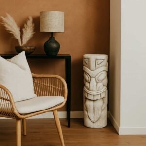 Statue Maori totem Tiki ton vieilli 51 cm - La statue Tiki s'adapte aussi bien en intérieur qu'en extérieur. Elle est ici représentée posée au sol dans l'angle d'un salon. (Mise en situation générée à titre indicatif - Visuel non contractuel)