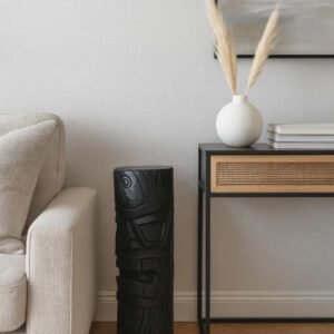 Statue Tiki totem Maori ton ciré noir 80 cm -La statue est posée au sol dans un salon à côté d'un canapé (Visuel non contractuel - Mise en situation générée à titre indicatif)