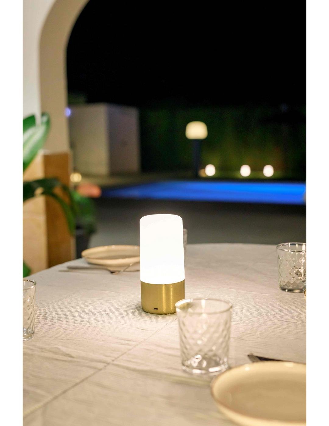 Lampe sans fil rechargeable Maia Or sur une table de jardin en soirée, référence D0108-9