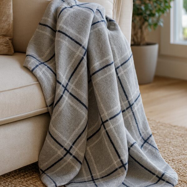 Plaid motif marron, noir et beige sur un canapé en cuir, près d'une cheminée. Illustration du confort et de la chaleur