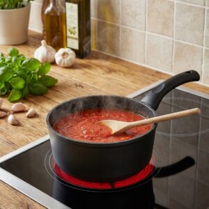 Casserole 18 B0046 en utilisation sur plaque chauffante, montrant son intérieur antiadhérent avec sauce