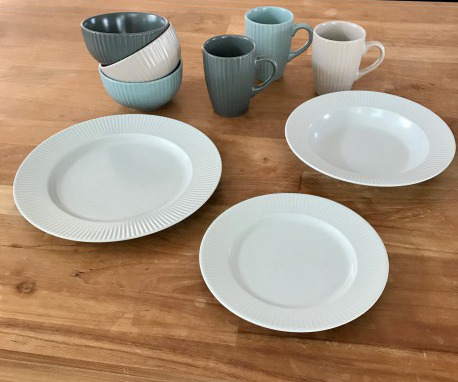 Ensemble de mugs en grès COTTAGE, assortis de différentes couleurs avec des assiettes sur une table en bois.