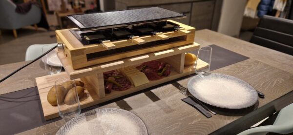 Planche à raclette en chêne massif avec raclette et garnitures sur table pour le produit MTR-2085210