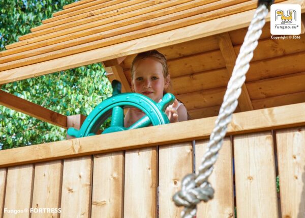 Enfant jouant au gouvernail dans l'aire de jeux géante en bois FUNGOO RAINBOW FORTRESS TIP, référence 3513PT
