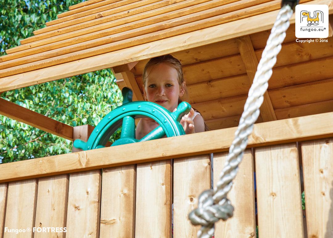 Enfant jouant au gouvernail dans l'aire de jeux géante en bois FUNGOO RAINBOW FORTRESS TIP, référence 3513PT