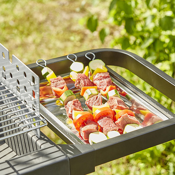 Vue rapprochée du barbecue à charbon en fonte EASY 60 CH042T avec brochettes sur plateau