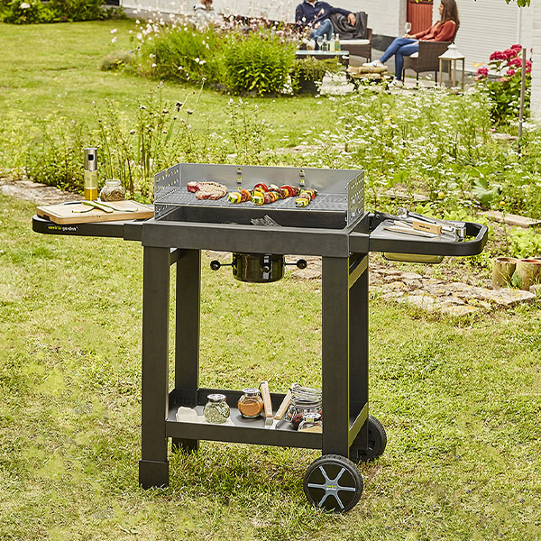 Barbecue à charbon en fonte EASY 60, photo principale dans un jardin avec accessoires, référence produit CH042T