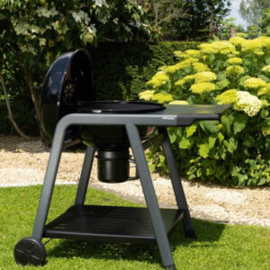 Vue principale du barbecue charbon rond avec couvercle TONINO 60, référence CH062T, présenté dans un jardin