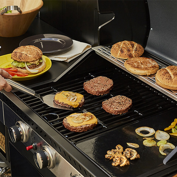 Barbecue gaz avec desserte FIDGI 3 en action, cuisson de burgers et légumes sur la grille et la plancha intégrées, référence COAM063SBI.