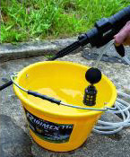 Nettoyeur moyenne pression avec batterie PRBAT20/NHP montré aspirant de l'eau depuis un seau, illustrant sa fonction d'aspiration automatique.