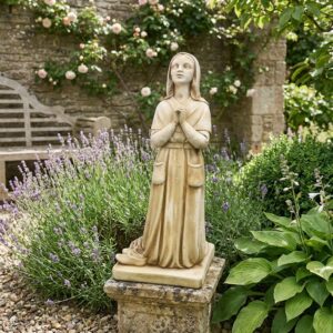 statue bernadette de lourdes - vue principale de la statue en pierre reconstituée dans un jardin fleuri - référence 215336